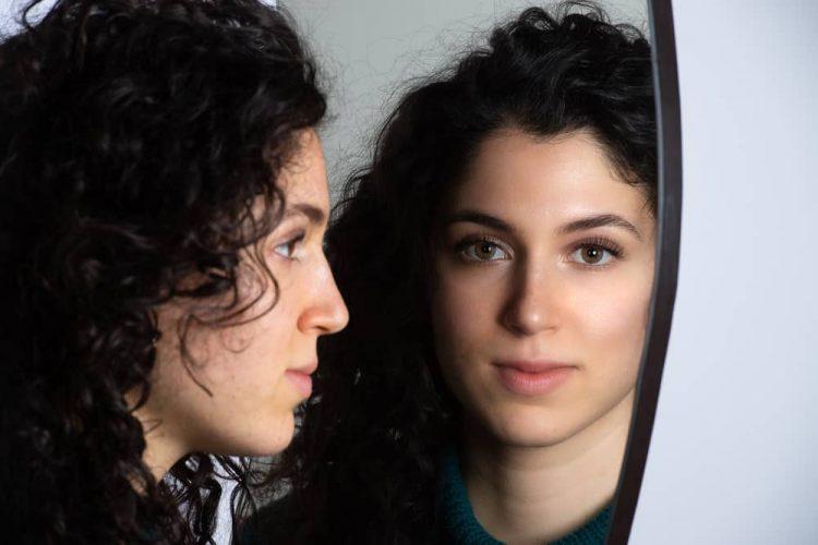 Image of a woman looking in the mirror with no self-compassion
